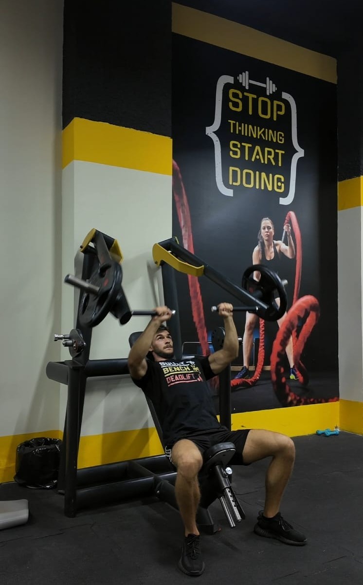 Erald, certified personal trainer with 7+ years of experience, posing confidently in a gym